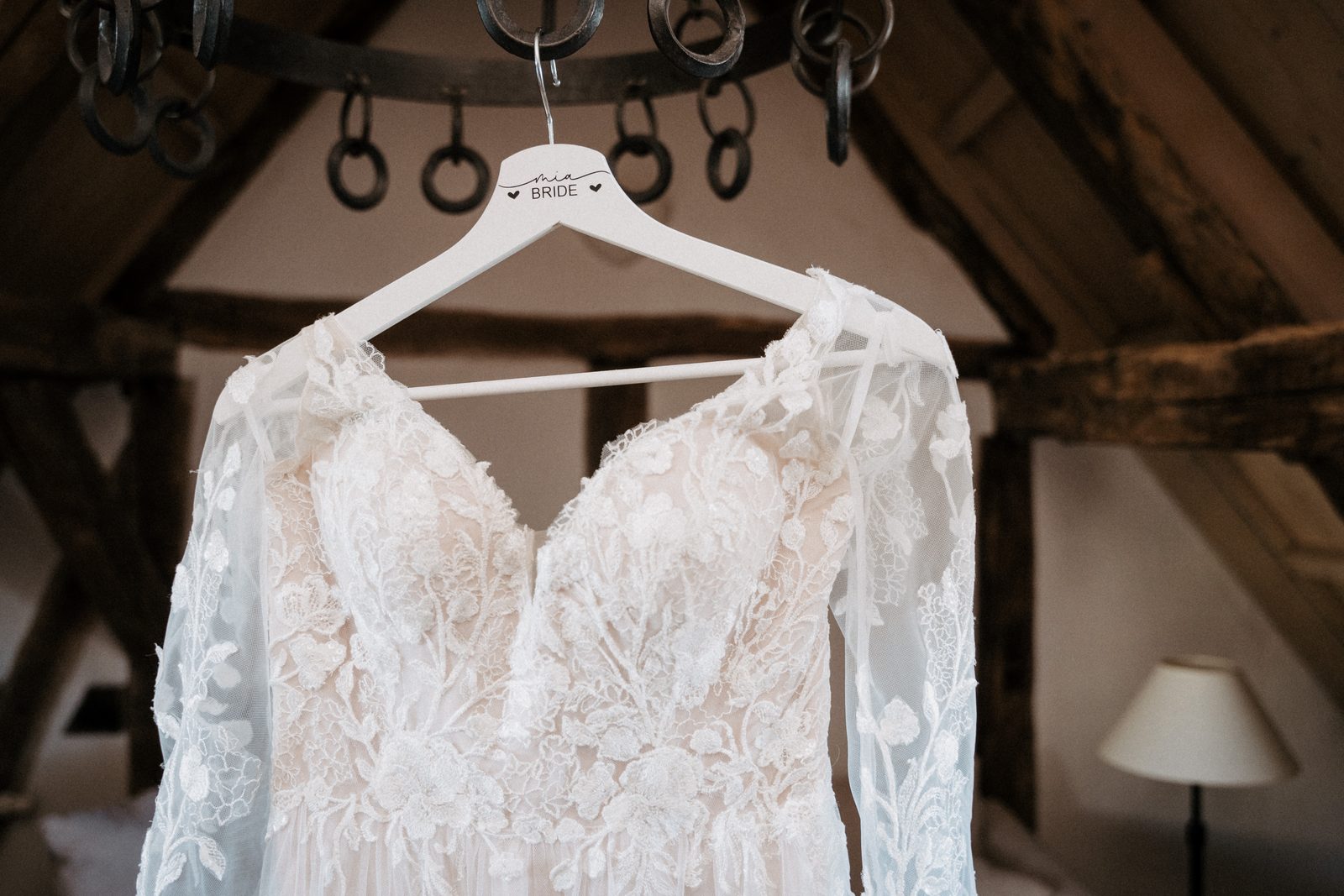 Das Brautkleid hängt am Balken, dahinter das Dachgebälk der Scheune