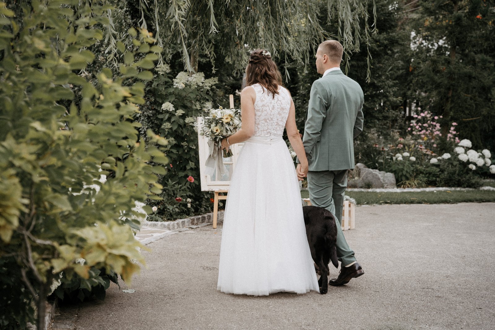 Brautpaar geht Hand in Hand durch den Garten