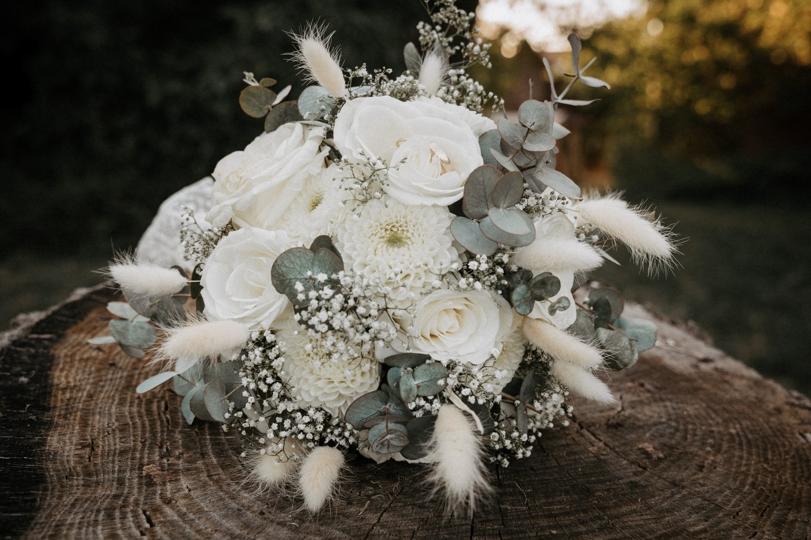 Brautstrauß aus weißen Rosen und Eukalyptus auf einer Holzscheibe
