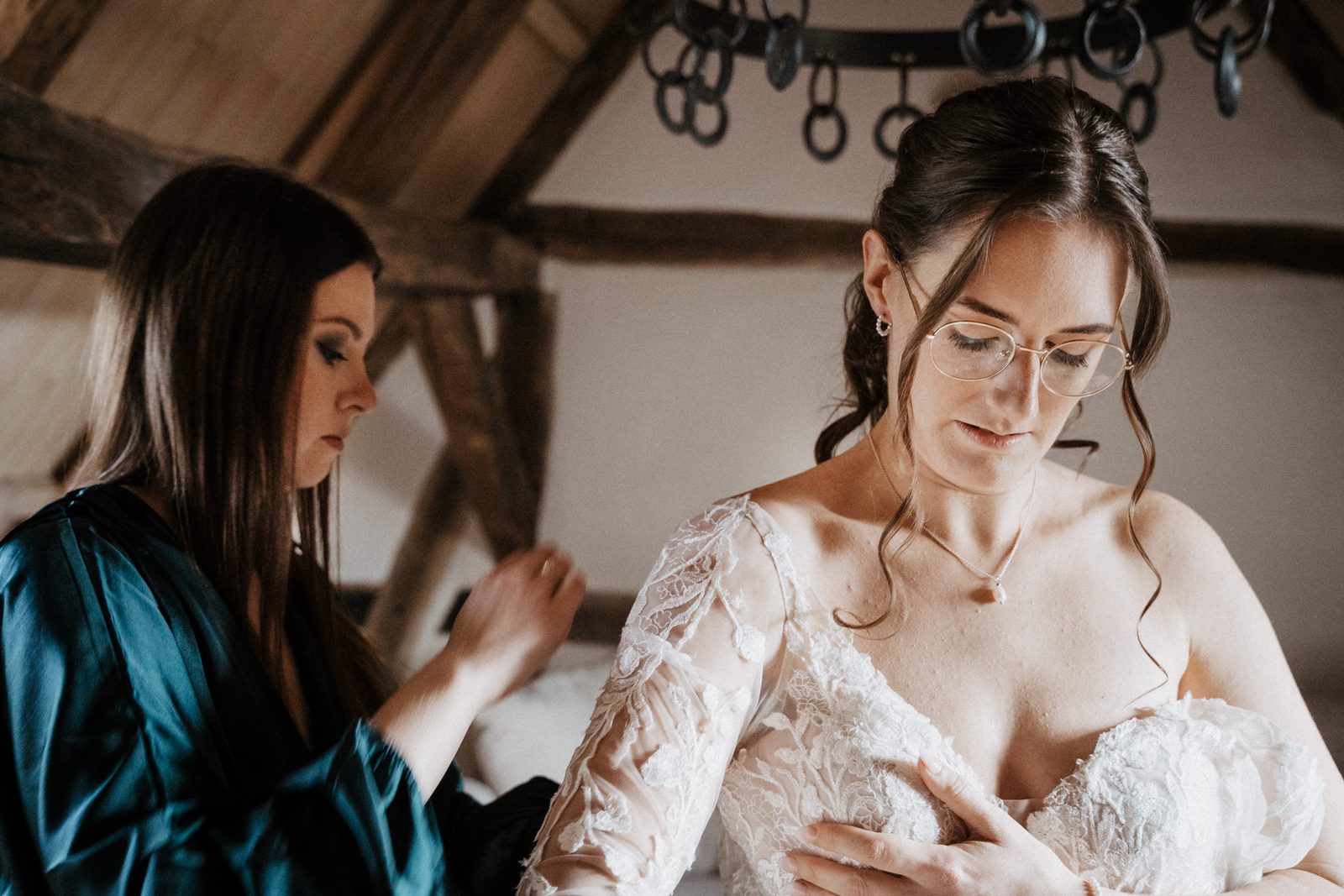 Die Braut zieht ihr Kleid an, eine Freundin hilft ihr von hinten
