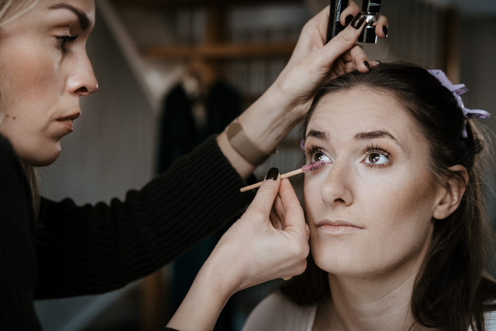 Stylistin schminkt die Braut am Morgen der Hochzeit, die Braut schaut nach oben