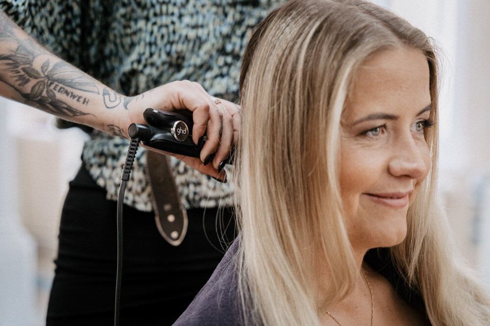 Braut lächelt beim Friseur, während ihre Haare gelockt werden