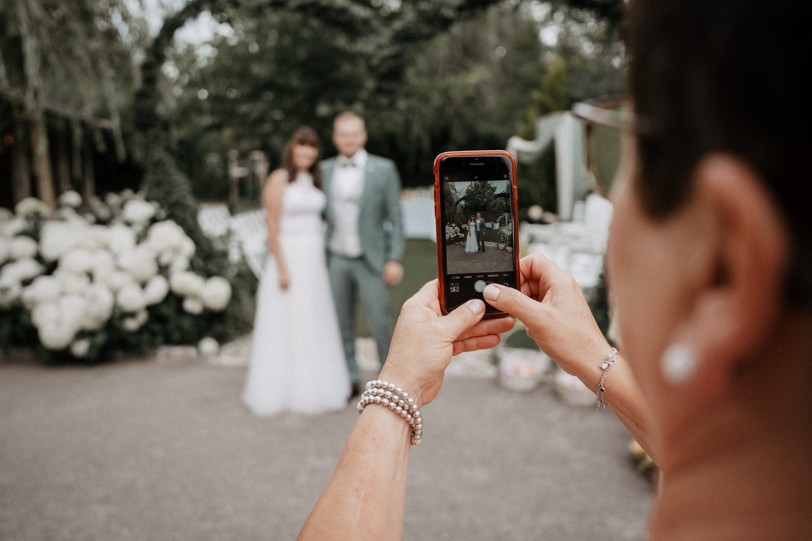 Ein Hochzeitsgast fotografiert das Brautpaar mit dem Handy