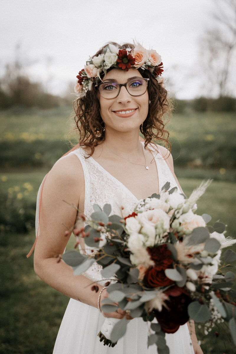 Braut mit Blumenkranz und Brautstrauß lacht in die Kamera