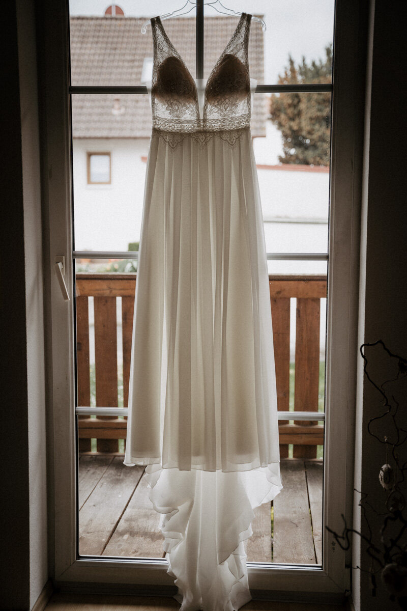Brautkleid hängt an der offenen Balkontür