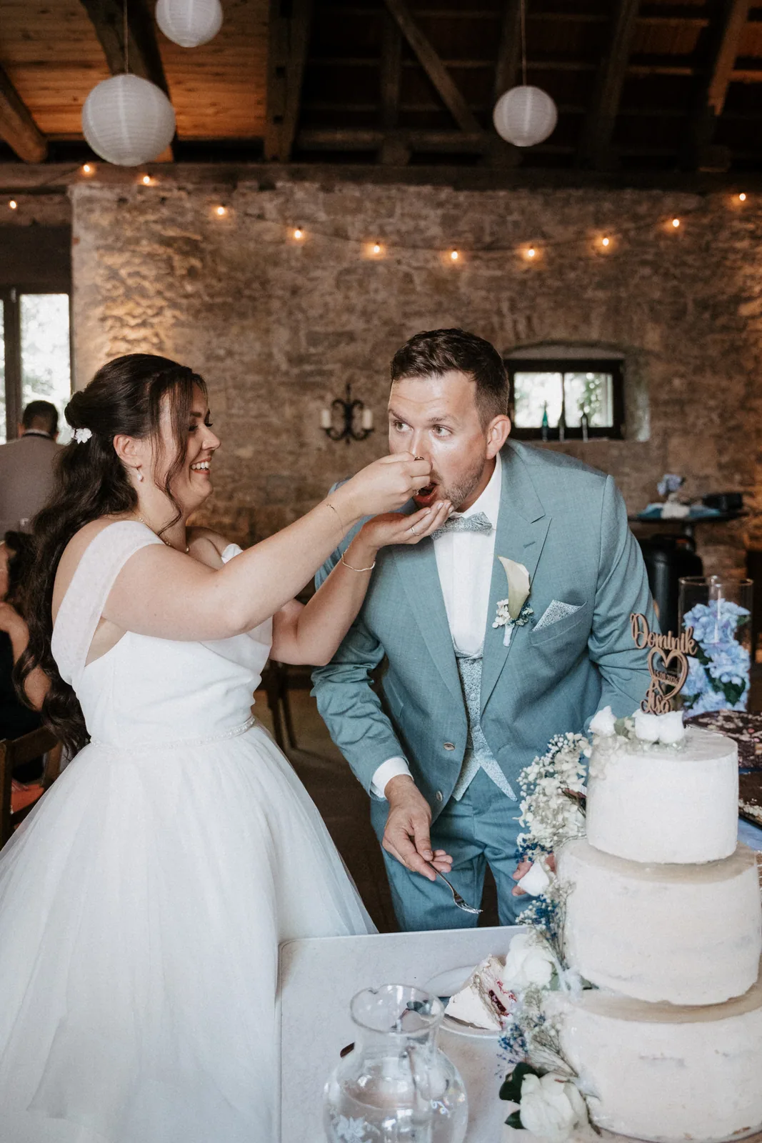 Braut füttert den Bräutigam mit einem Stück Hochzeitstorte im Gewölbe der Uhlenmühle in Aub