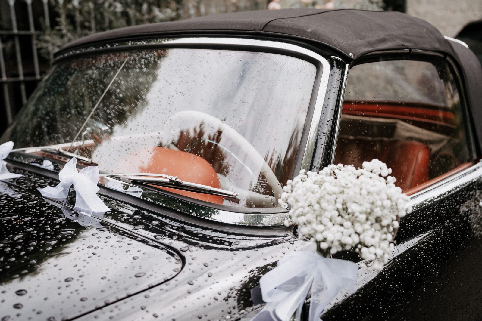 Oldtimer mit Blumenschmuck auf der Motorhaube, Regentropfen auf dem Lack