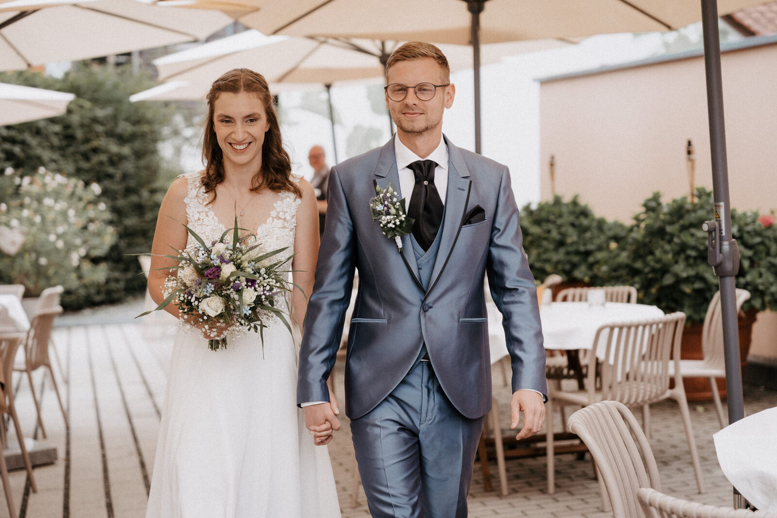 Brautpaar zieht Hand in Hand in den Garten des Schindlerhofs ein