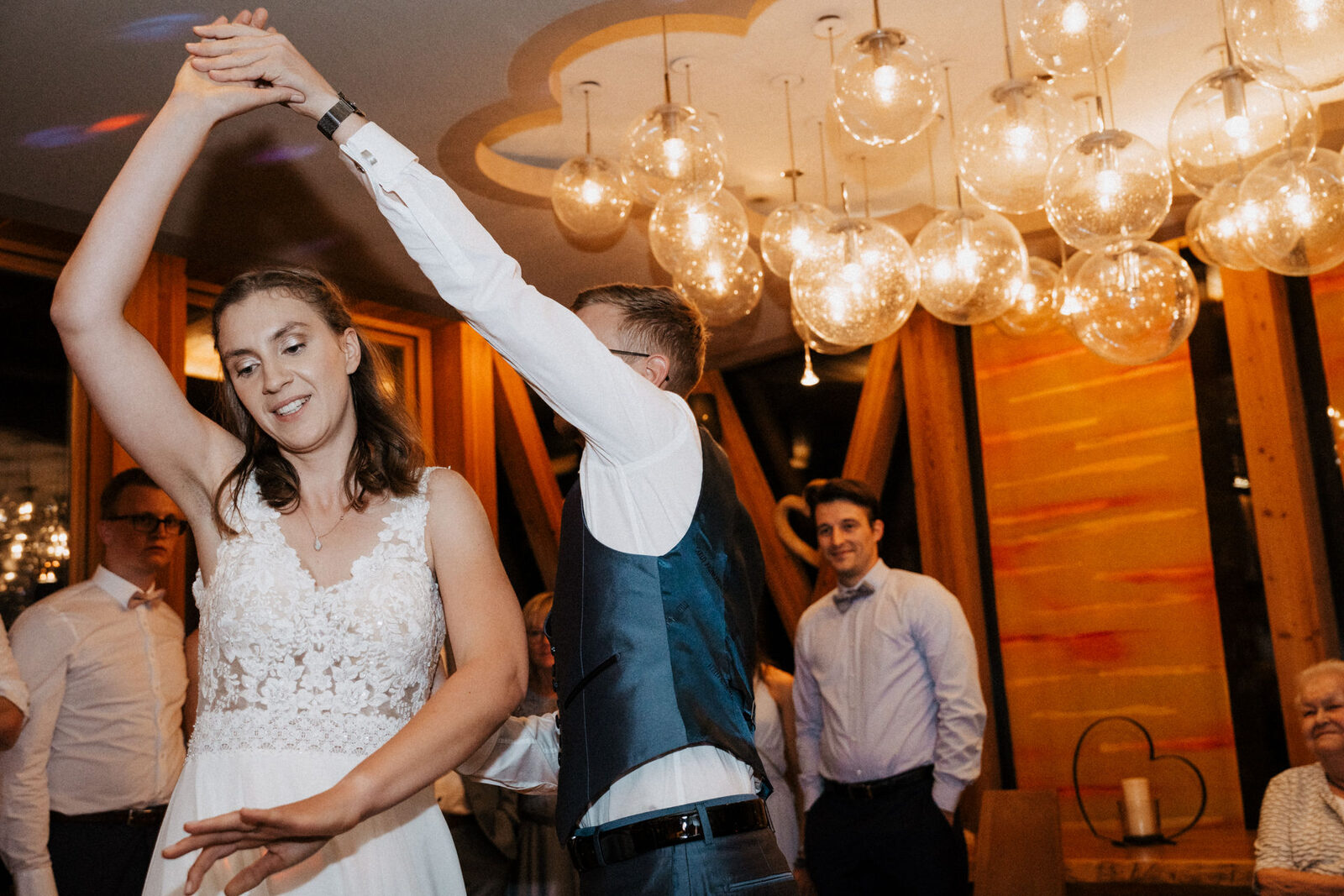 Braut dreht sich beim Hochzeitstanz unter den Lampen im Saal