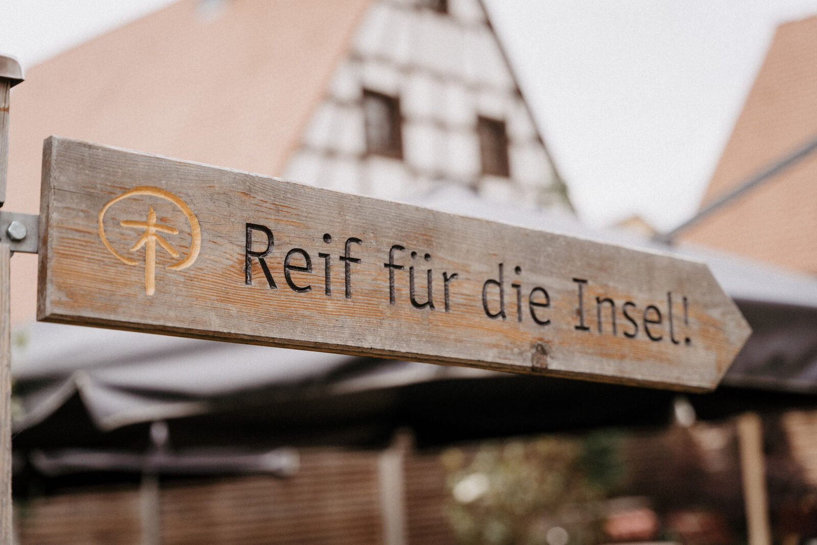 Holzschild mit der Aufschrift Reif für die Insel im Garten des Schindlerhofs