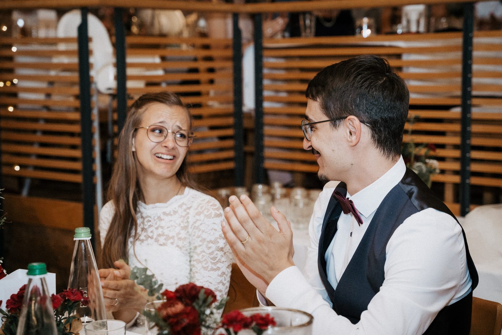 Brautpaar sitzt an der festlich gedeckten Tafel in der Scheune und stößt an