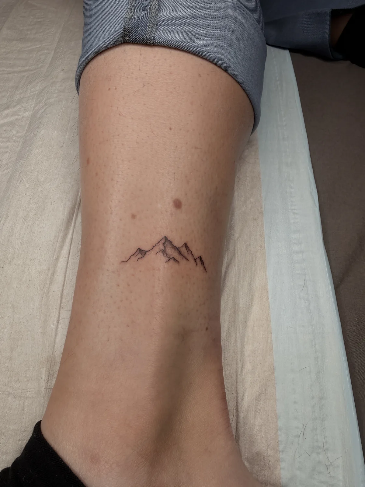 Tattoo auf der Hochzeit, kleines Berg-Motiv am Knöchel, frisch gestochen