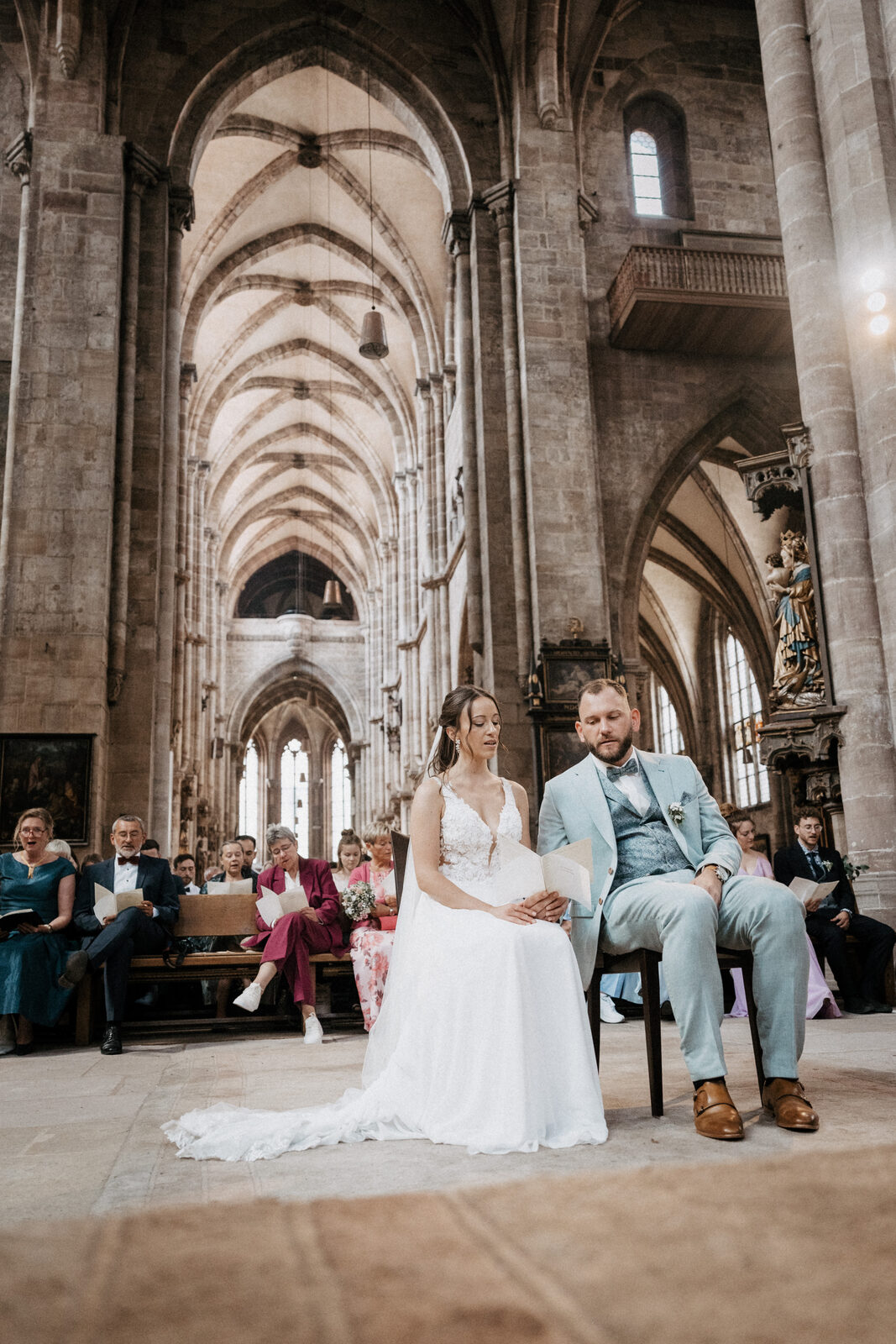 Brautpaar sitzt vorne in der Sebalduskirche, darüber das hohe gotische Gewölbe