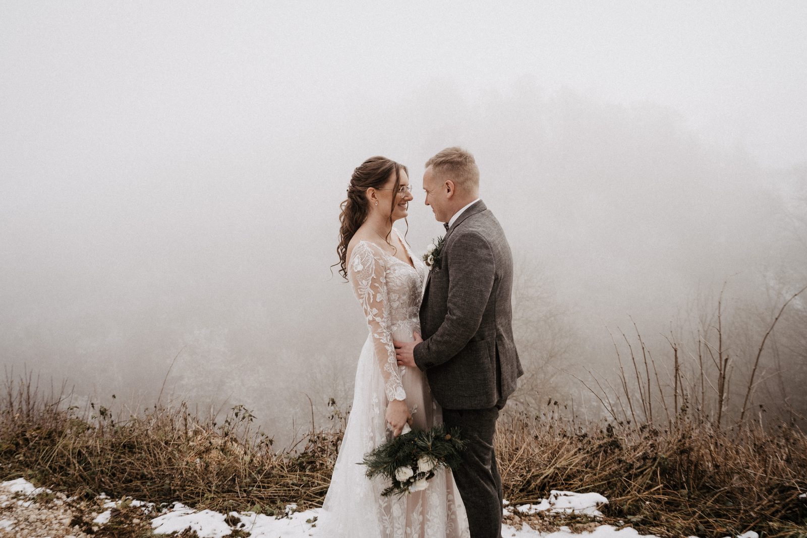 Brautpaar im Nebel bei einer Winterhochzeit auf der Schwäbischen Alb, hinter ihnen verschwindet die Landschaft