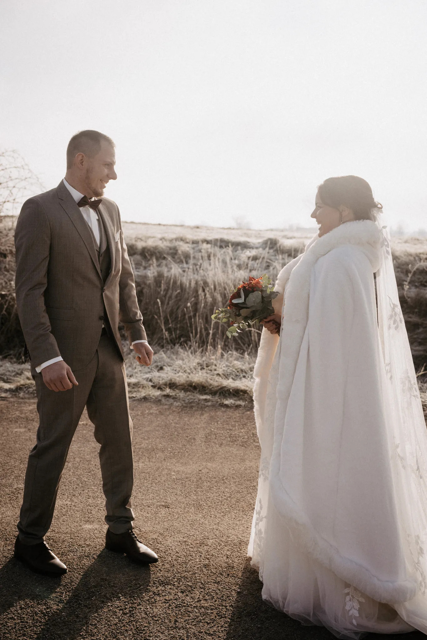 Brautpaar umarmt sich im Gegenlicht, der Schleier weht, Winterhochzeit bei Rothenburg