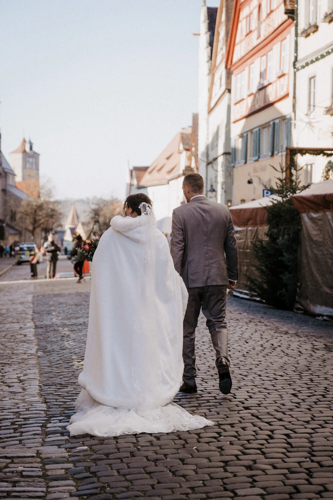 Brautpaar geht über das Kopfsteinpflaster einer Gasse in Rothenburg ob der Tauber, im Hintergrund Fachwerk und ein Stadtturm