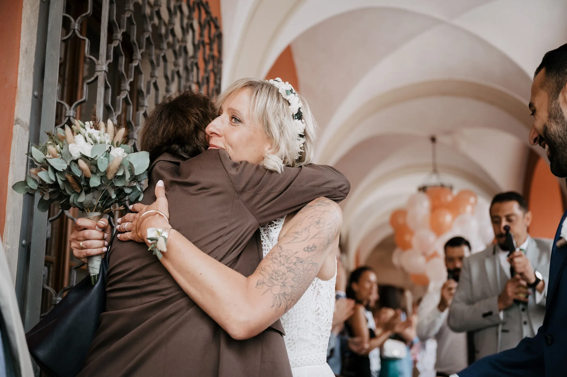 Braut umarmt nach der Trauung einen Gast unter den Arkaden vor dem Rathaus Neustadt an der Aisch