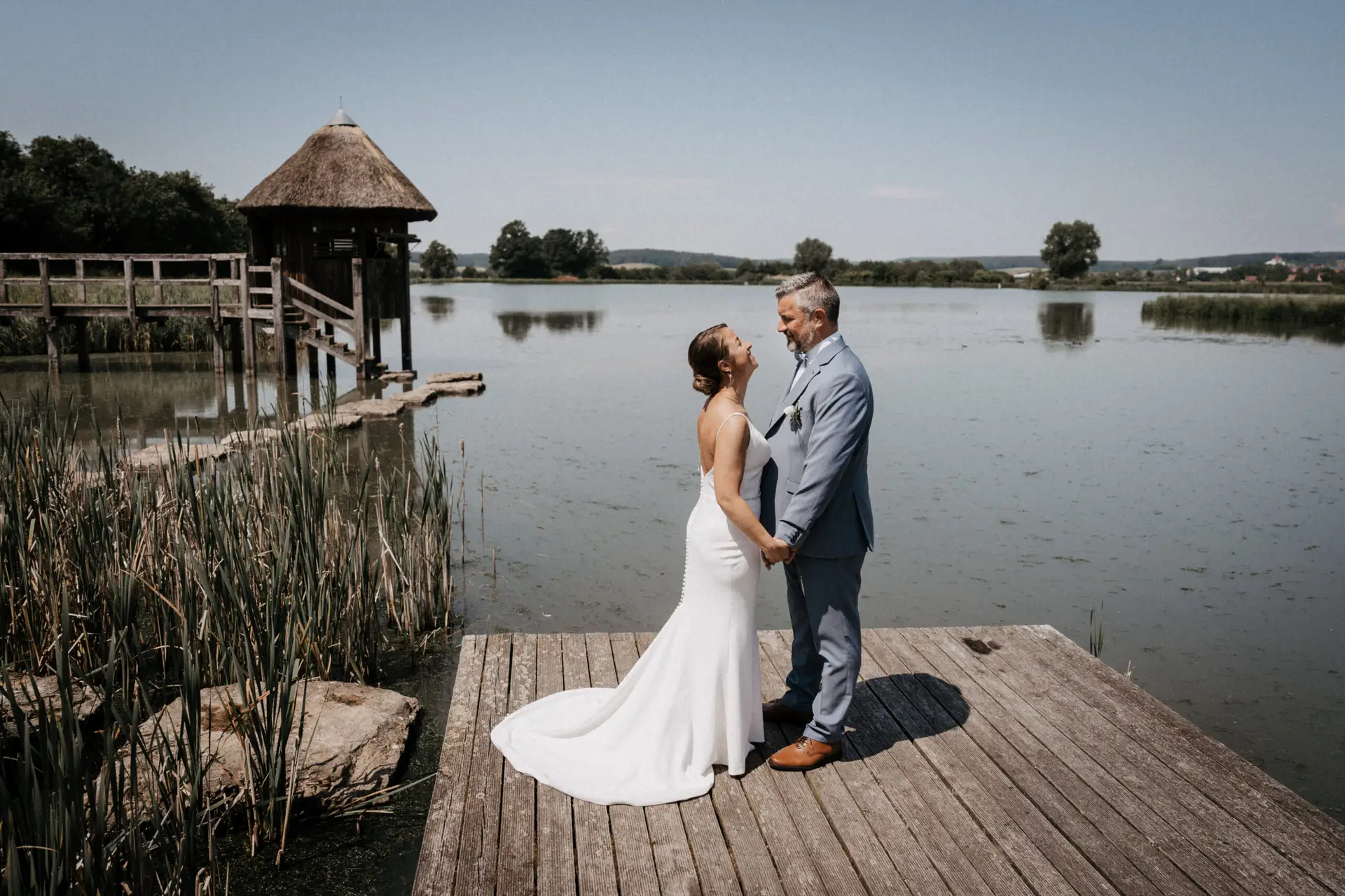 hochzeit neustadt aisch Brautpaar steht händehaltend auf Steg am Uehlfeld See