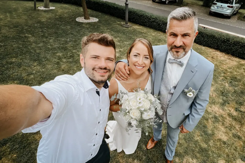 Brautpaar und der Hochzeitsfotograf Neustadt strahlen gemeinsam in die Kamera